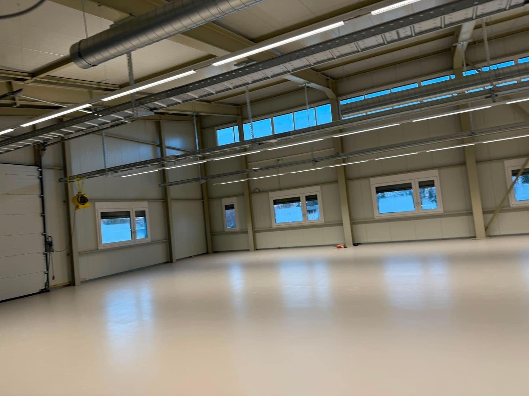 Gewerbehalle mit Fensterband unter dem Dach und hellem Boden