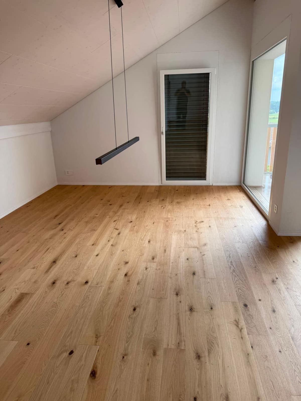 Leeres Zimmer mit Dachschräge und Parkett, übergabefertig