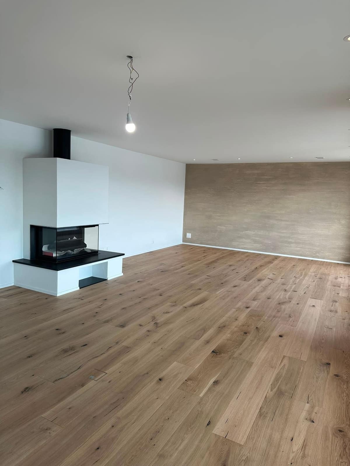 Leerer Wohnraum mit Cheminée und Parkett